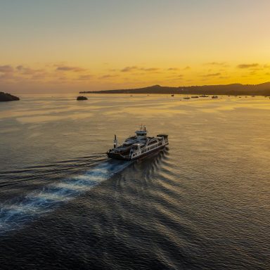 Barge naviguant sur la mer au coucher de soleil, en direction de la Petit Terre.