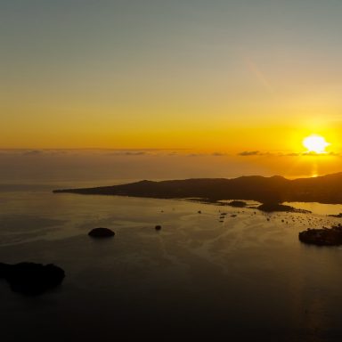 Coucher de soleil sur une côte avec des îles, illuminant l'horizon.